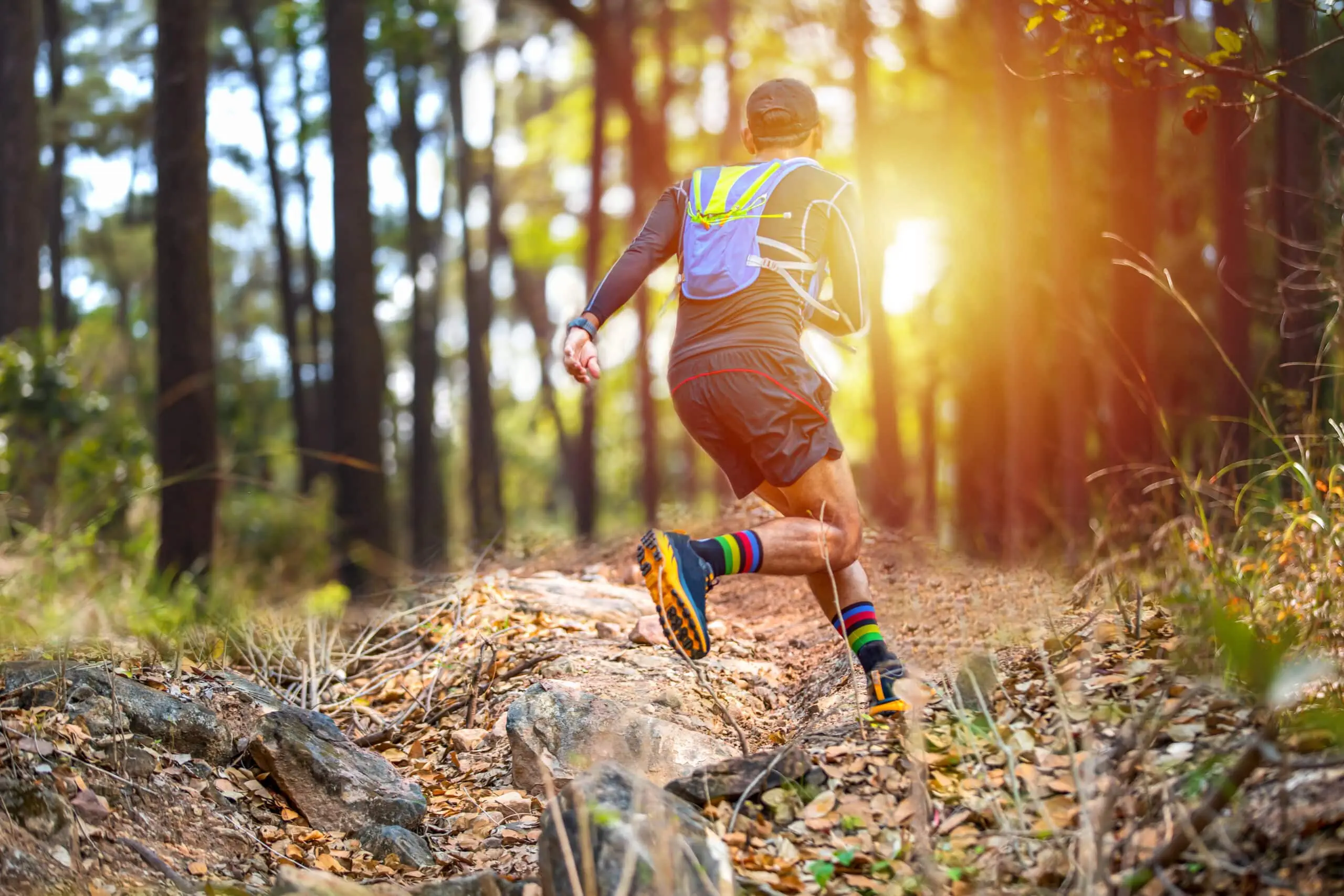 A,Man,Runner,Of,Trail,And,Athlete's,Feet,Wearing,Sports | What Race To Run A man, running on a trail with sun and trees in the background